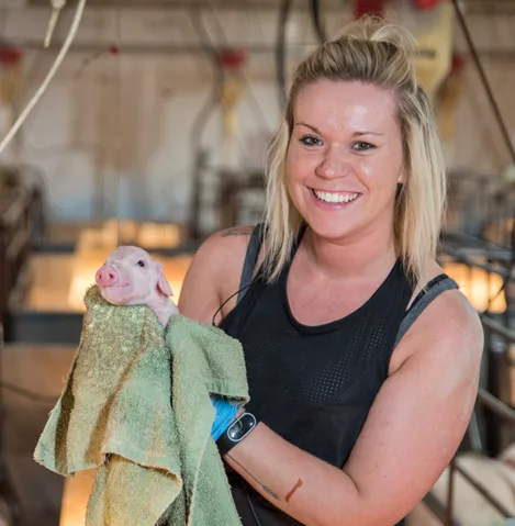 Woman holding a tiny piglet in a towel