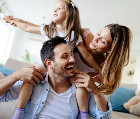Father with daughter on his shoulders laughing with the mother.