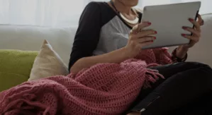 Woman sitting on a couch reading a tablet